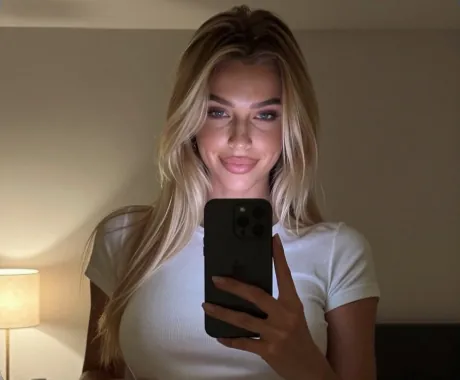 Realistic AI girlfriend taking a mirror selfie in a white t-shirt